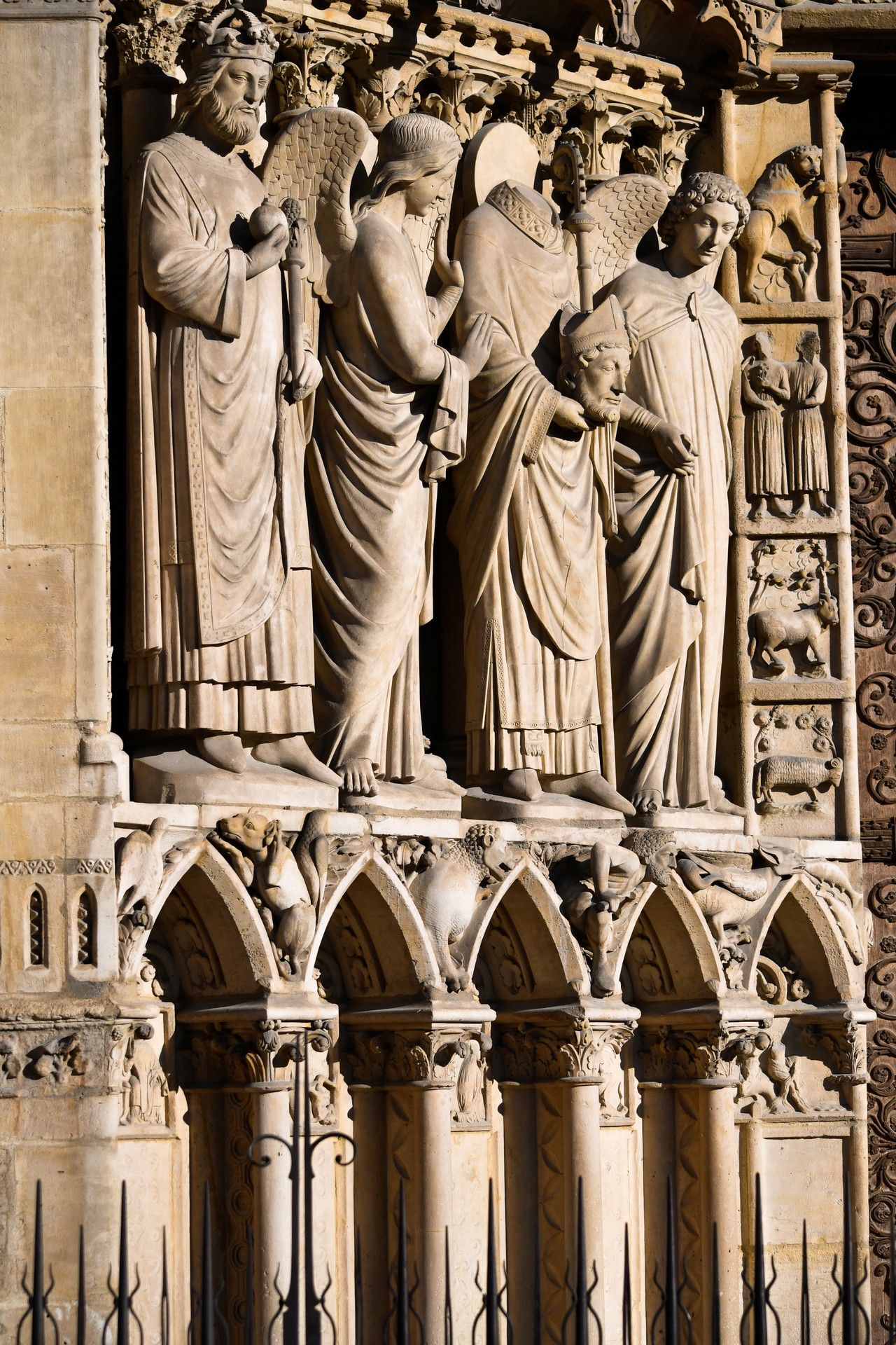 Détail d'un portail de la cathédrale Notre-Dame de Paris. Les écoinçons en bas. Les grandes statues de l'empereur Constantin, d'anges et de saint Denis, et enfin, à droite, on aperçoit les signes du zodiaque.